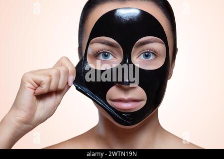 Eine schwarze Maske auf das Gesicht einer schönen Frau. Spa-Behandlungen und Katzenpflege im Schönheitssalon. Stockfoto