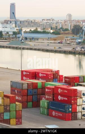 Sevilla, Spanien - 2. Juni 2023: Mehrere farbenfrohe Schiffscontainer werden ordentlich an einem Hafenterminal gestapelt, mit Kränen im Hintergrund, Sug Stockfoto