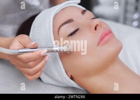 Der Kosmetologe macht das Verfahren Microdermabrasion der Gesichtshaut einer schönen, jungen Frau in einem Schönheitssalon.Cosmetologie und professionell Stockfoto