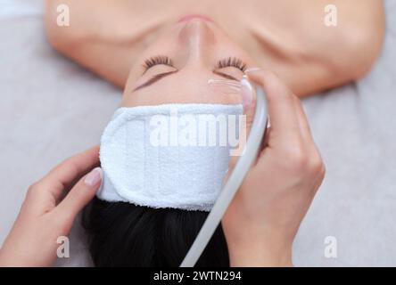 Der Kosmetiker macht das Verfahren der Gesichtsreinigung einer schönen, jungen Frau in einem Schönheitssalon. Kosmetik und professionelle Hautpflege. Stockfoto