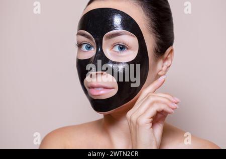 Eine schwarze Maske auf das Gesicht einer schönen Frau. Spa-Behandlungen und Katzenpflege im Schönheitssalon. Stockfoto