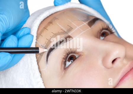 Permanent Make-up für Augenbrauen einer schönen Frau mit dicken Augenbrauen im Schönheitssalon. Nahaufnahme-Kosmetikerin, die Augenbrauen tätowiert. Stockfoto