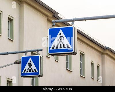 Fußgängerübergangsschild in Deutschland. Die Beschilderung befindet sich neben einem Zebramuster auf der Straße. Verkehrssymbol für Autofahrer, damit sie auf Menschen aufmerksam sind. Stockfoto