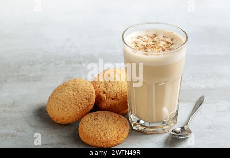 Kaffee-Raff in einem Glas Nahaufnahme mit hausgemachten Keksen. Kaffee mit Milch und geriebener Nuss auf hellem Hintergrund Stockfoto
