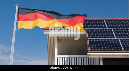 Deutsche Flagge flattert auf dem Dach mit Solarpaneelen Stockfoto