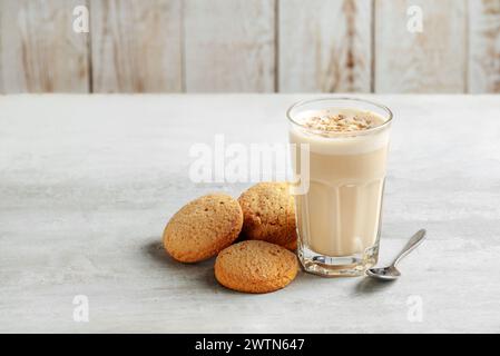 Kaffee-Raff in einem Glas Nahaufnahme mit hausgemachten Keksen. Kaffee mit Milch und geriebener Nuss auf hellem Hintergrund Stockfoto