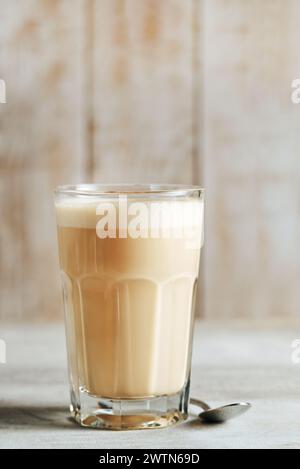 Rapskaffee in einem transparenten Glas auf hellem Holzhintergrund. Kaffee mit Milch. Stockfoto