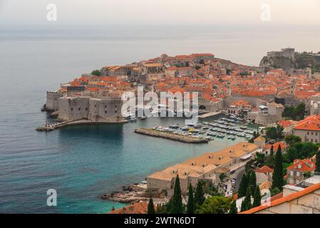 Blick aus der Vogelperspektive auf die Altstadt von Dubrovnik mit türkisfarbenem Wasserhafen an der Adria bei Sonnenuntergang, Dalmatien, Kroatien. Mittelalterliche Festung mit Booten und Yachten Stockfoto