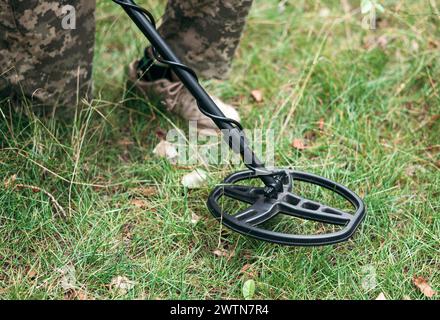 Soldat, der einen Metalldetektor auf dem Feld benutzt. Ukrainischer Sprengstoffentsorgungsbeamter detektiert Metall mit Metalldetektorgerät. Stockfoto