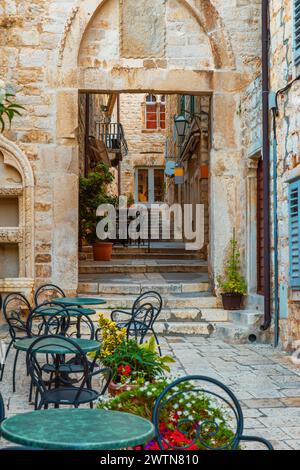 Straßencafé mit Tischen und Stühlen draußen in einer alten gemütlichen Straße in der alten mittelalterlichen Stadt Hvar in Outdoor Restaurant mit niemand, Dalmatien, Kroatien Stockfoto