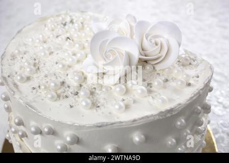 Weißer Partykuchen mit weißer Glasur und Perlen, Kuchendesign. Handgemachter Kuchen für einen besonderen feierlichen Anlass. Besondere Details. Stockfoto