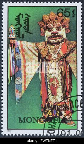 Von der Mongolei gedruckte Briefmarke, die Masken und Kostüme zeigt, um 1991. Stockfoto