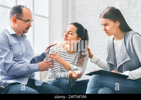 Besorgte Unterstützungsgruppe mebers tröstet emotionale junge Frau bei Therapiesitzung Stockfoto