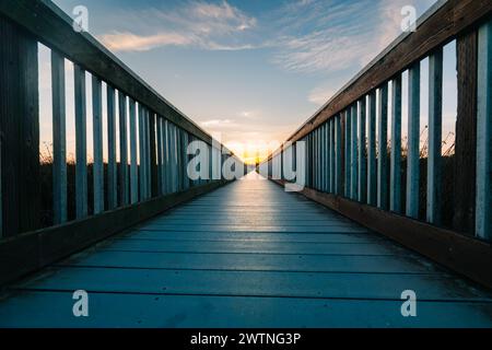 Ein langer Holzsteg scheint sich bis ins Unendliche zu erstrecken. Weg zum Himmel bei Sonnenuntergang, Konzept, Kopierraum für den Text Stockfoto