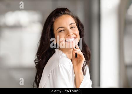 Porträt einer fröhlichen, schönen jungen brünetten Frau im Badezimmer Stockfoto