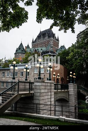 Blick auf das Chateau Frontenac am frühen Morgen mit beleuchteten Lampen über die Brücke und Bäumen, die das historische Hotel umrahmen. Stockfoto