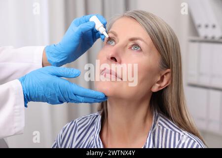 Medizinische Tropfen. Doktor tropft Medikamente in das Auge der Frau drinnen Stockfoto