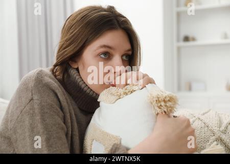 Traurige junge Frau, die zu Hause auf dem Sofa sitzt Stockfoto