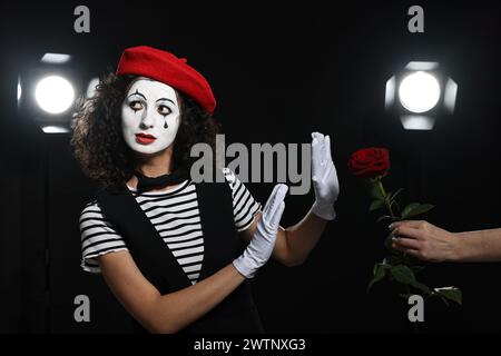 Ein Mann gibt der jungen Frau rote Rose im Mime-Kostüm auf der Bühne Stockfoto