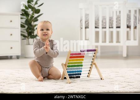 Kinderspielzeug. Süßer kleiner Junge und hölzerner Abakus auf Teppich zu Hause Stockfoto