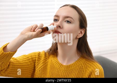 Medizinische Tropfen. Junge Frau mit Nasenspray in Innenräumen Stockfoto