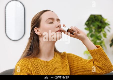 Medizinische Tropfen. Junge Frau mit Nasenspray in Innenräumen Stockfoto