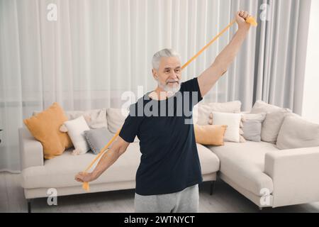 Seniorenmann, der zu Hause Sport mit elastischem Fitnessband macht Stockfoto