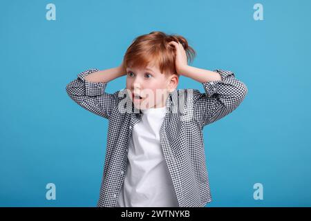 Überraschter kleiner Junge auf hellblauem Hintergrund Stockfoto