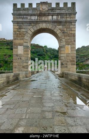 Triumphbogen der Trajanbrücke in Alcantara, römische Steinbogenbrücke, kleiner römischer Tempel auf der linken Uferseite im Hintergrund, Caceres, Spanien Stockfoto