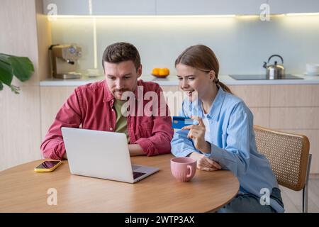 Familien-Paar-Shopaholics kaufen online mit einem Laptop und geben das Budget über eine Bankkarte aus Stockfoto