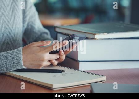 Nahaufnahme der Hand mit dem Smartphone, das Daten in der Bibliothek sucht. Stockfoto