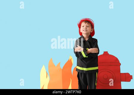 Netter kleiner Feuerwehrmann mit Papierhydrant und Flamme auf blauem Hintergrund Stockfoto