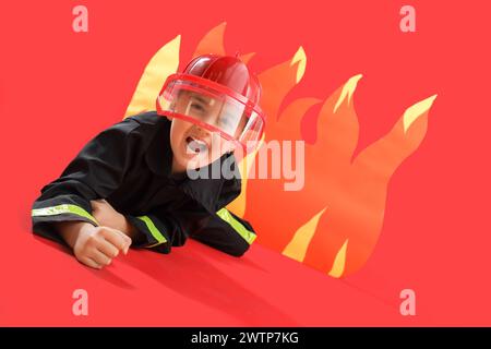 Verängstigte kleine Feuerwehr, die vor Papierflamme auf rotem Hintergrund liegt Stockfoto