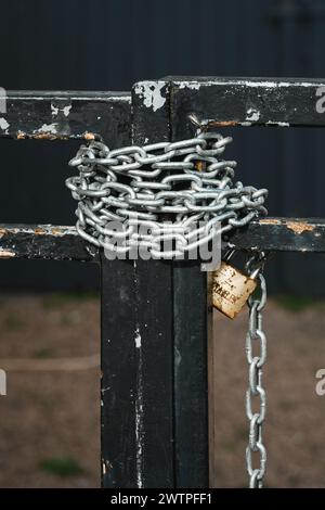 Kette um ein Tor gewickelt und mit einem Vorhängeschloss verschlossen Stockfoto