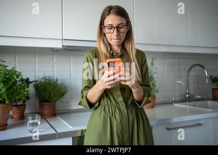 Verwirrte frustrierte blonde Frau in Brille, die Nachrichten im Smartphone schreibt, Waren online kauft Konzept Stockfoto