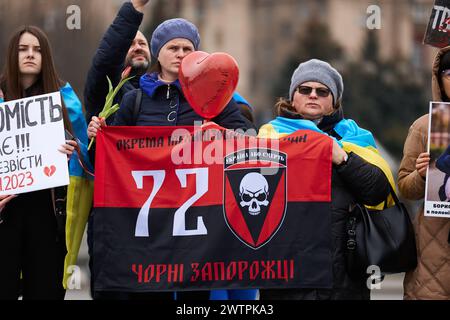 Ukrainische Frauen halten eine Flagge der 72. Brigade der schwarzen Zaporoschets bei der öffentlichen Demonstration, die den gefangenen Verteidigern der Ukraine gewidmet ist. Kiew - 16. März 2024 Stockfoto