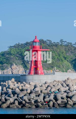 Leuchtend roter Leuchtturm auf einem Steg mit Tetrapodenwellenbrechern in Sinjin-Do, Südkorea, Asien Stockfoto