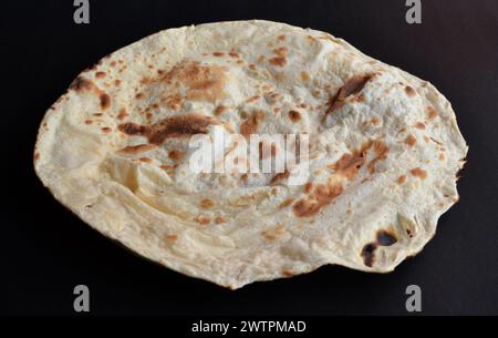 Irani Roti ist ein Fladenbrot aus Vollweizen, das traditionell in Tandoor gekocht wird. Eine Nahaufnahme, isoliert auf schwarzem Hintergrund. Stockfoto