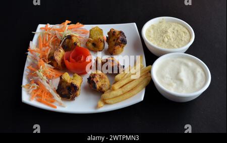 Owsal-Hühnchen mit Pommes frites serviert mit Mayonnaise. Eine Nahaufnahme isoliert auf schwarzem Hintergrund. Stockfoto