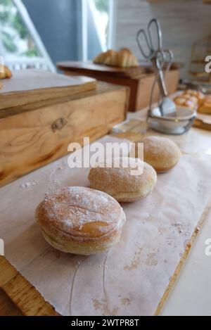 Bomboloni, krapfen oder Donuts auf einem Holztisch. Hausgemachte gebratene Donuts gefüllt mit Vanillepudding und mit einem Schleier Zucker gewürzt. Stockfoto