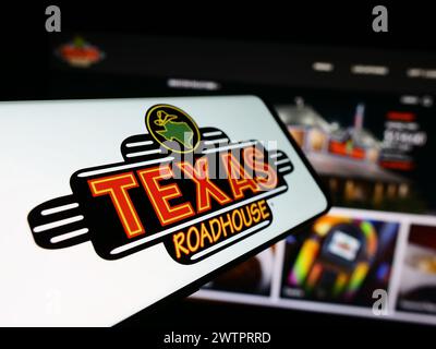 Mobiltelefon mit Logo des amerikanischen Steakhouse-Restaurantunternehmens Texas Roadhouse Inc. Vor der Website. Fokus auf der linken Seite des Telefondisplays. Stockfoto