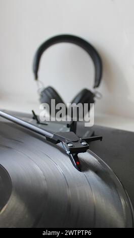 Head Of Vinyl Record Player Auf Disc Vor Defokussierten Schwarzen Kopfhörern Auf Weißem Hintergrund Stockfoto