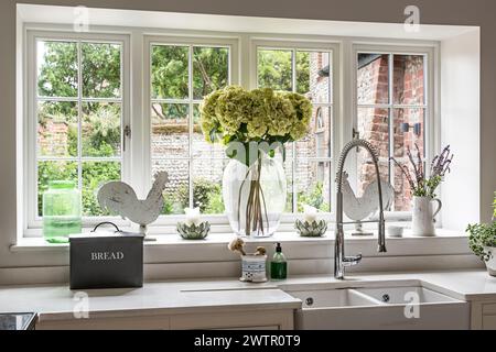 Hortensien in Glasvase auf Fensterbank in der britischen Küche, Blakeney, Norfolk, UK Stockfoto