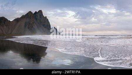 Sonnenaufgang Stokksnes Cape Meeresstrand und Vestrahorn Berg mit seiner Reflexion auf nassen schwarzen vulkanischen Sandoberfläche, Island. Erstaunliche Naturlandschaft, popu Stockfoto