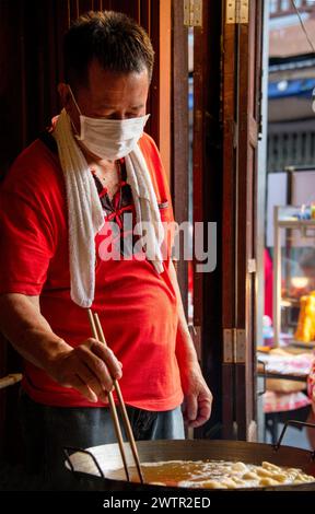 Jomtien, Thailand, 10. Februar 2024: Chakngeaw Chinese Village. Ein Paar macht Youtiao, einen langen goldbraunen, frittierten Streifen Weizenmehlteig. Stockfoto
