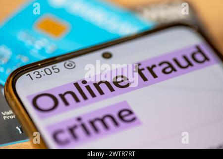 Eine Makroaufnahme eines Mobiltelefons mit den Worten Online-Betrug Verbrechen auf Kredit, Debit-Bankkarten. Ein Konzept der Online-Betrugskriminalität. Stockfoto