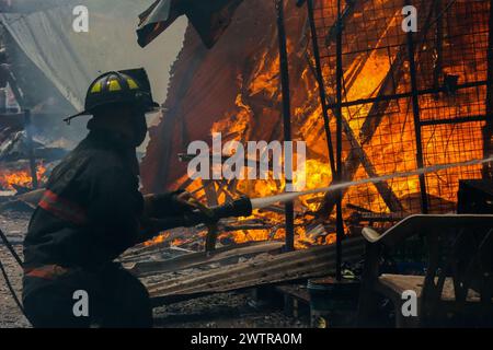 Quezon City, Philippinen. März 2024. Ein Feuerwehrmann versucht, die Flamme am Ort eines Feuerunfalls in Quezon City, den Philippinen, am 19. März 2024 zu löschen. Nach Angaben der örtlichen Behörden waren etwa 400 Familien von einem Feuerunfall betroffen, der sich am Dienstag in Quezon City ereignete. Quelle: Rouelle Umali/Xinhua/Alamy Live News Stockfoto