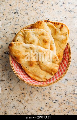 Frisch gebackenes Naan-Brot im Korb auf einem Küchentisch. Draufsicht. Stockfoto