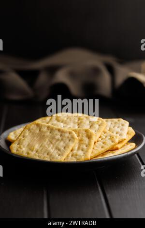 Gesalzene Cracker auf einer schwarzen Platte vor dunklem Hintergrund Stockfoto