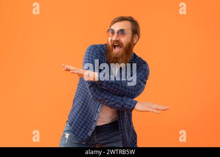 Lustiger, fröhlicher rothaariger Mann mit Bart in Sonnenbrille tanzen, Studio Stockfoto